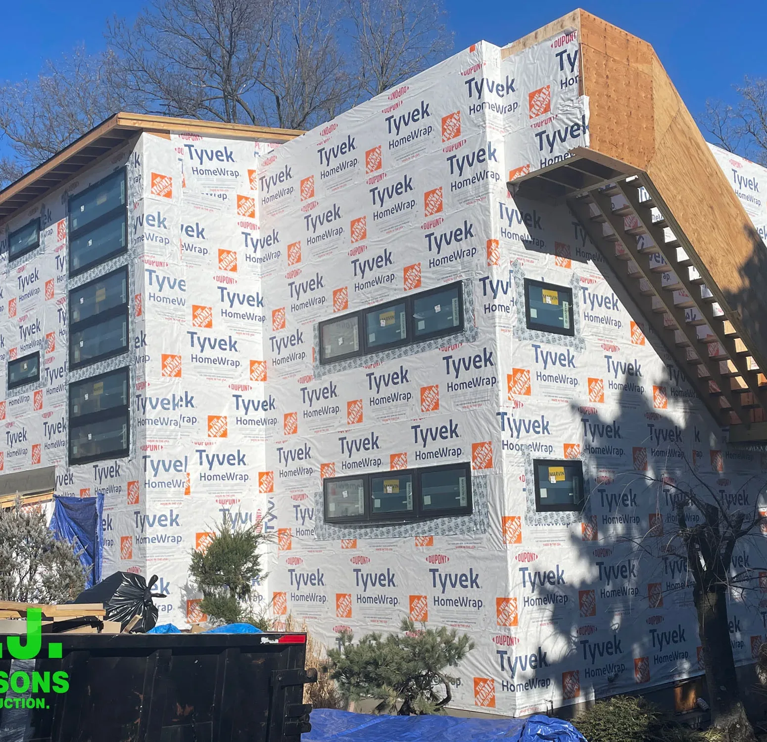 Image capturing the initial stages of home construction, showcasing a bare house structure with house wrap, preparing for the installation of Nichiha siding.